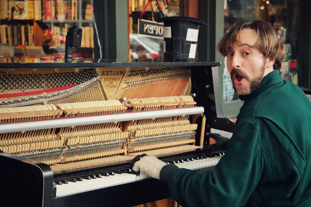 A skilled musician dressed in a vibrant green sweater passionately plays the piano, creating enchanting melodies that resonate through the air. This captivating scene captures the joy and expressiveness of live music performance, making it ideal for use in articles, advertisements, or promotional materials related to music education, concerts, or artistic expression.